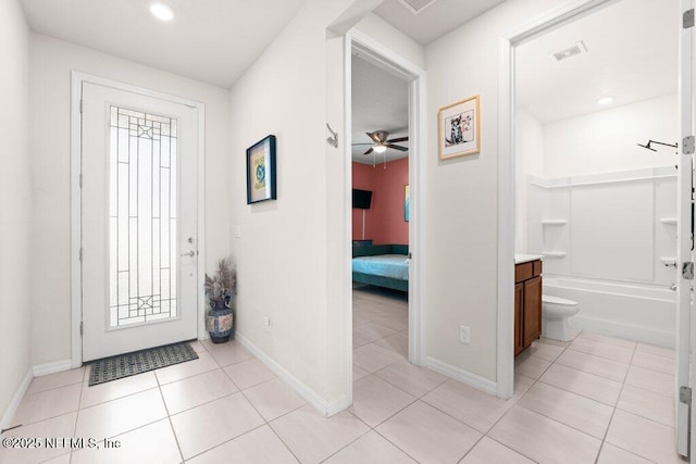 foyer entrance with light tile patterned floors, visible vents, baseboards, and a ceiling fan