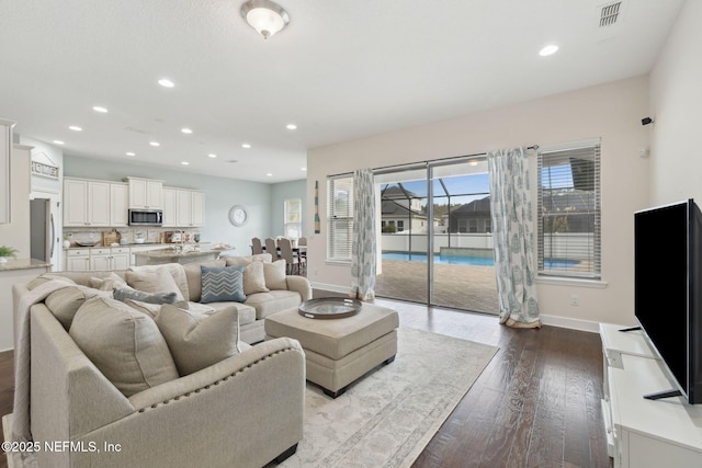 living room featuring dark wood-type flooring, recessed lighting, visible vents, and baseboards