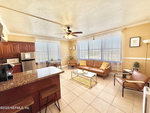 tiled living room with a textured ceiling, ceiling fan, and ornamental molding