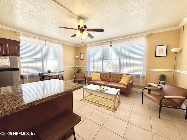 tiled living room featuring a textured ceiling, plenty of natural light, ceiling fan, and ornamental molding