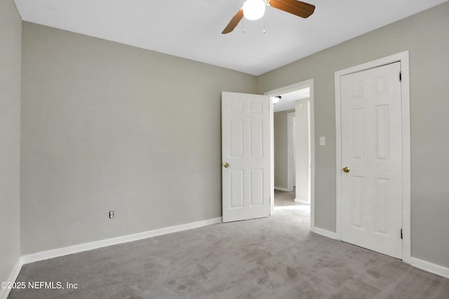 interior space featuring baseboards, a ceiling fan, and light colored carpet