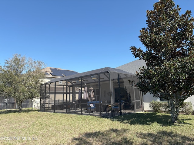 back of house with a patio, a yard, glass enclosure, and solar panels