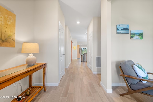 hallway featuring light wood finished floors, baseboards, visible vents, and recessed lighting