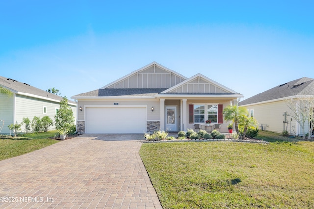 view of front of property with a garage, stone siding, decorative driveway, a front lawn, and board and batten siding