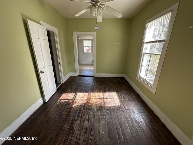 unfurnished room with dark wood-type flooring, baseboards, and a ceiling fan