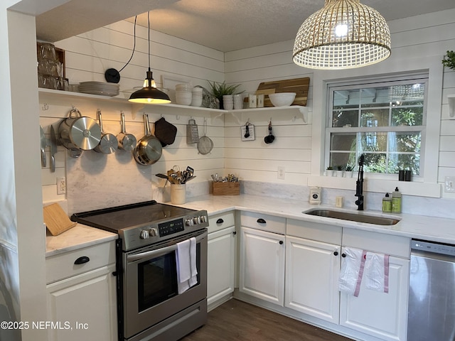 kitchen featuring wooden walls, a sink, white cabinets, appliances with stainless steel finishes, and open shelves