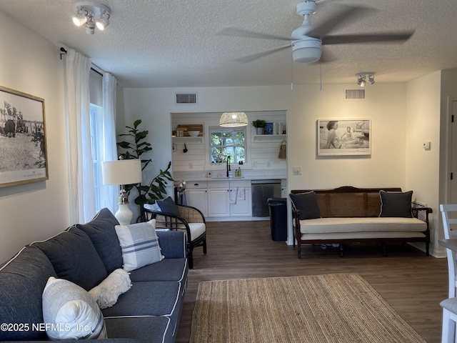 living room featuring a textured ceiling, dark wood-style flooring, and visible vents