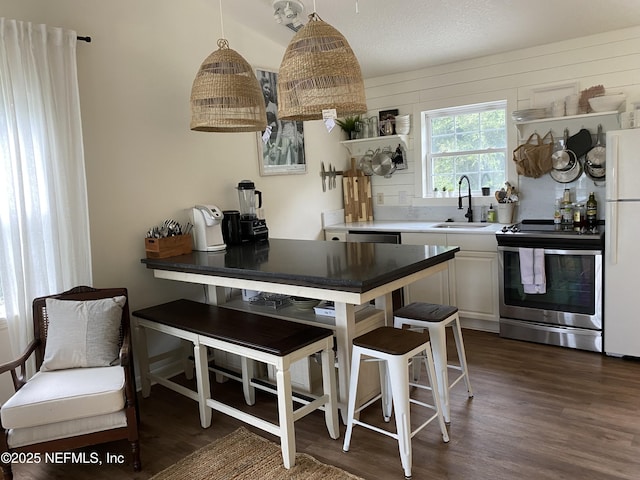 kitchen featuring electric range, dark wood-style flooring, freestanding refrigerator, a textured ceiling, and a sink