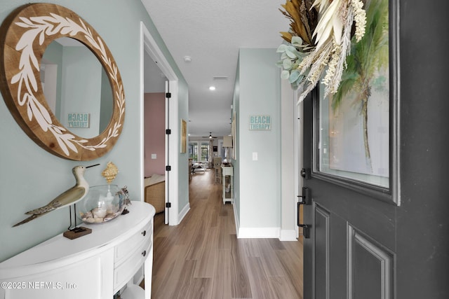 entryway featuring a textured ceiling, wood finished floors, and baseboards