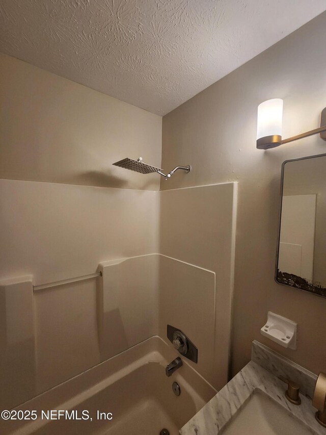 full bathroom with shower / bathtub combination, a textured ceiling, and a sink