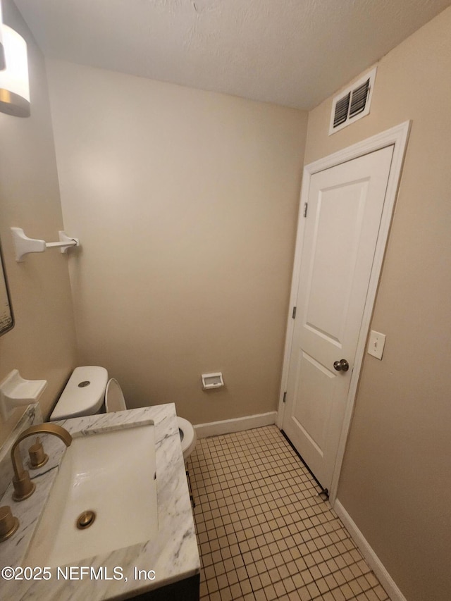 interior space with baseboards, visible vents, a sink, and toilet