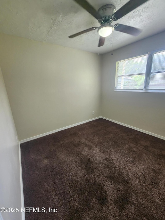 unfurnished room featuring dark colored carpet, ceiling fan, a textured ceiling, and baseboards