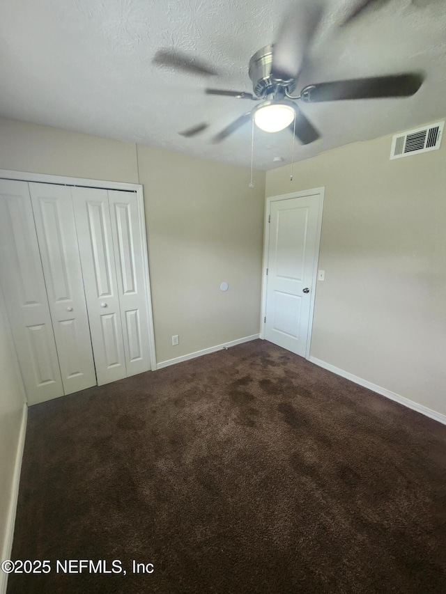 unfurnished bedroom with baseboards, visible vents, a textured ceiling, carpet flooring, and a closet