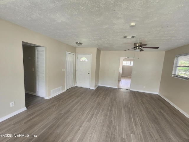 unfurnished living room featuring visible vents, baseboards, and wood finished floors