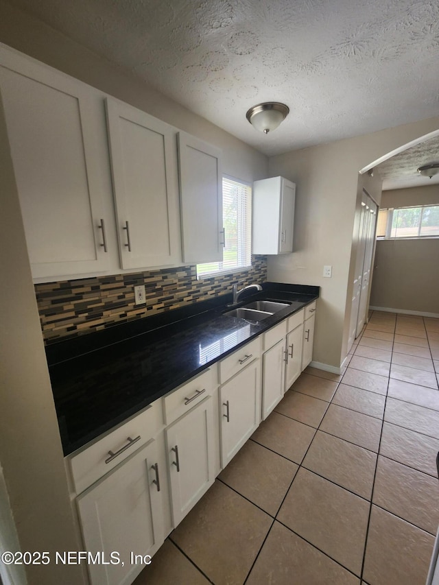 kitchen featuring white cabinets, decorative backsplash, a sink, and light tile patterned flooring