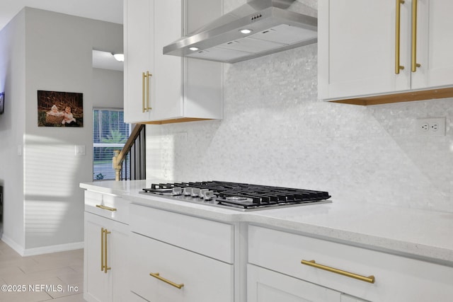 kitchen featuring white cabinets, stainless steel gas cooktop, ventilation hood, and backsplash