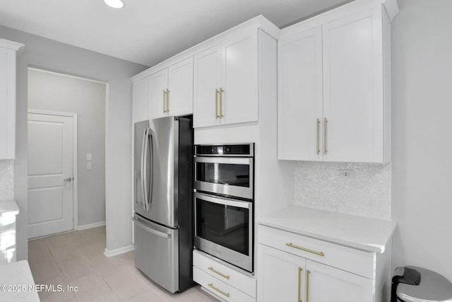 kitchen featuring baseboards, white cabinets, stainless steel appliances, light countertops, and backsplash