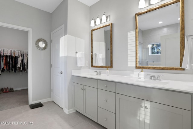 full bathroom featuring double vanity, tiled shower, tile patterned flooring, and a sink