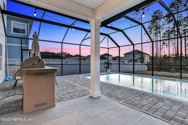 pool at dusk featuring glass enclosure, a fenced in pool, area for grilling, and a patio