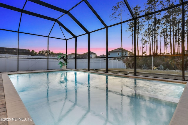 pool at dusk with glass enclosure, a patio area, and a fenced in pool