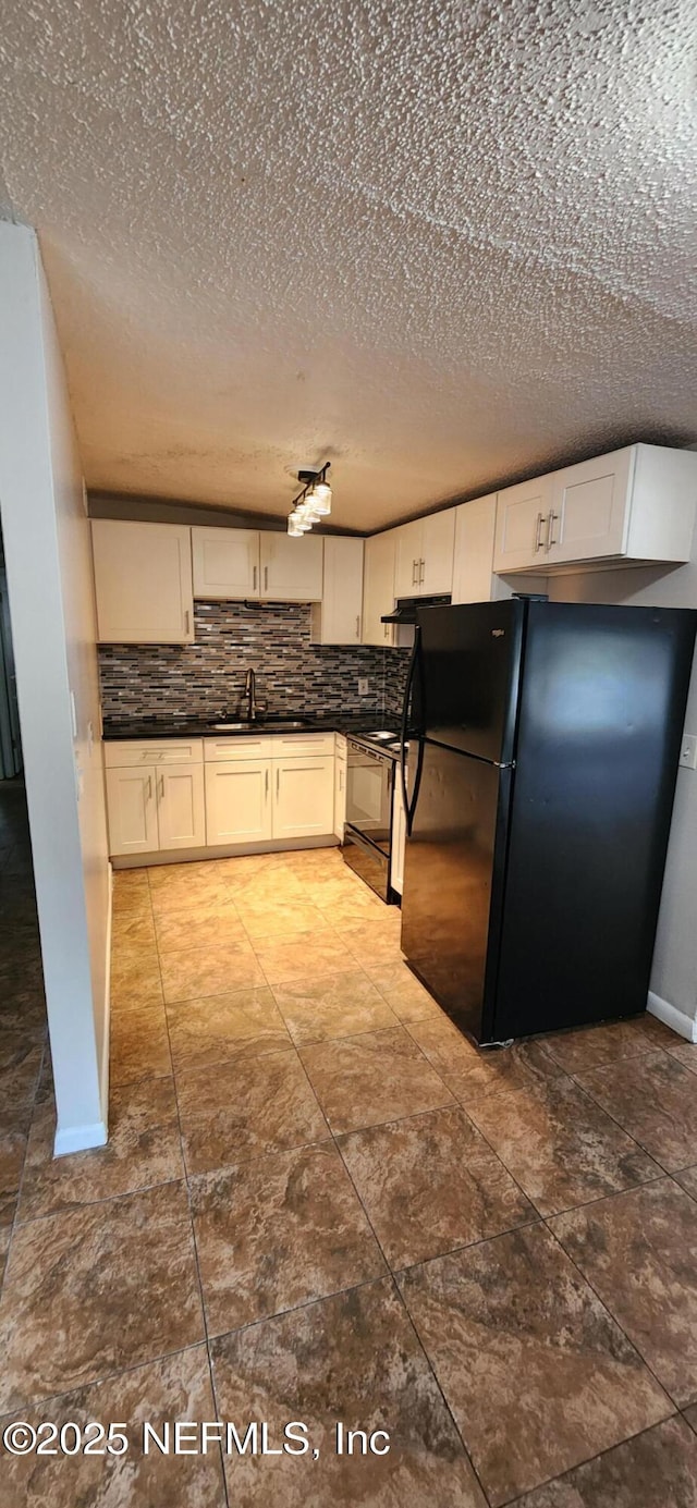 kitchen with dark countertops, backsplash, black appliances, white cabinetry, and a sink