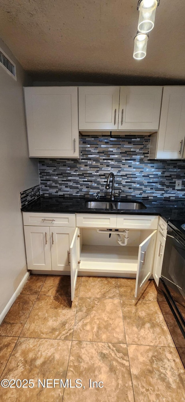 kitchen with range, dark countertops, a sink, and decorative backsplash