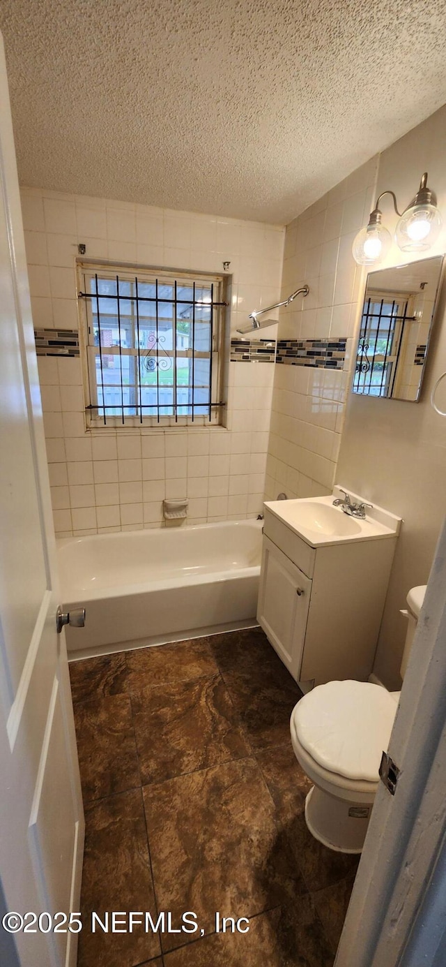 bathroom with a textured ceiling, shower / bathing tub combination, vanity, and toilet