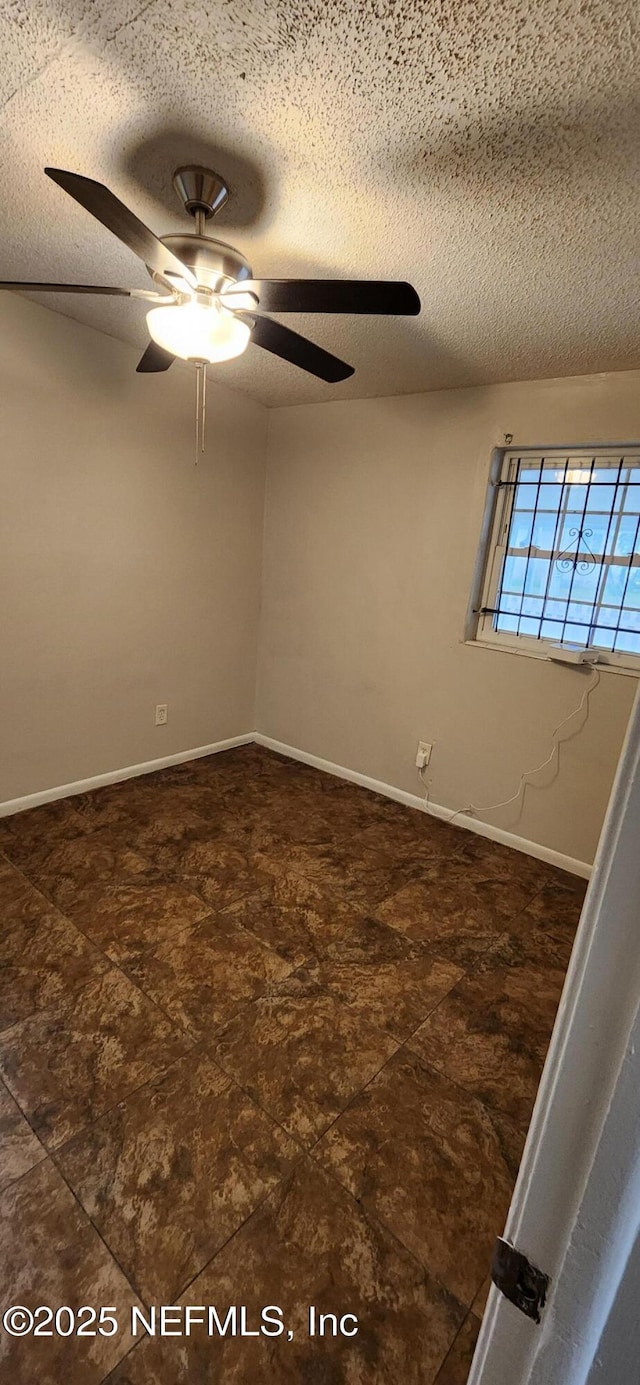 spare room with ceiling fan, baseboards, and a textured ceiling