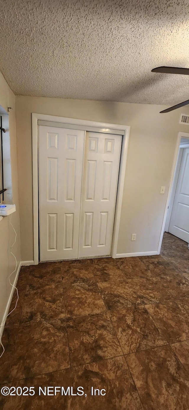 unfurnished bedroom featuring a closet, visible vents, a ceiling fan, a textured ceiling, and baseboards