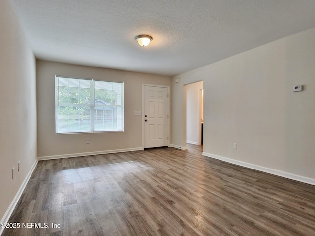 unfurnished room with dark wood-style floors, a textured ceiling, and baseboards