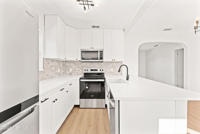 kitchen featuring a sink, a peninsula, stainless steel appliances, and light countertops