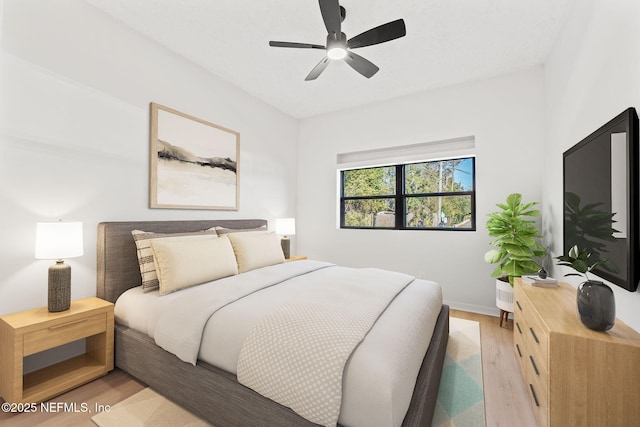 bedroom with light wood finished floors, a ceiling fan, and baseboards