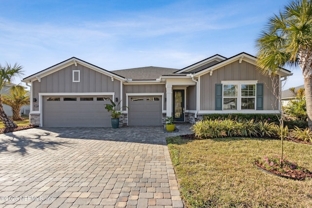 view of front of home featuring a garage, decorative driveway, board and batten siding, and a front yard