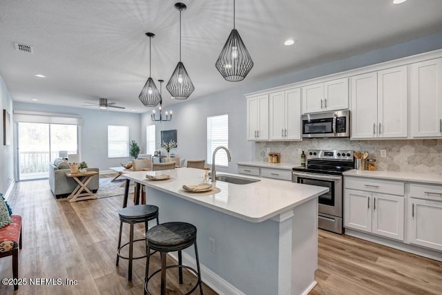 kitchen featuring sink, stainless steel appliances, white cabinetry, and pendant lighting