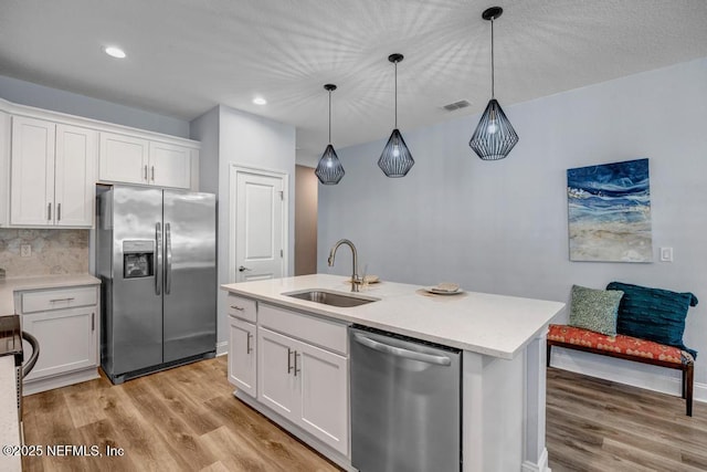 kitchen with sink, stainless steel appliances, white cabinetry, and pendant lighting