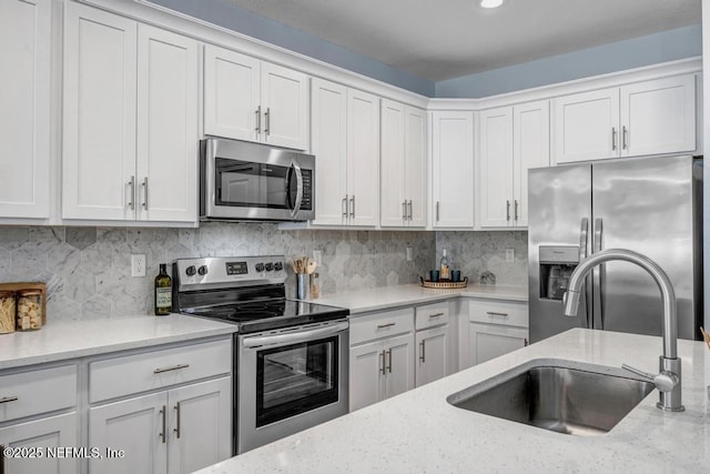 kitchen featuring sink, white cabinets, stainless steel appliances, and light stone counters