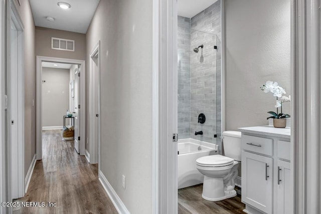 full bathroom featuring vanity, tiled shower / bath, toilet, and hardwood / wood-style floors