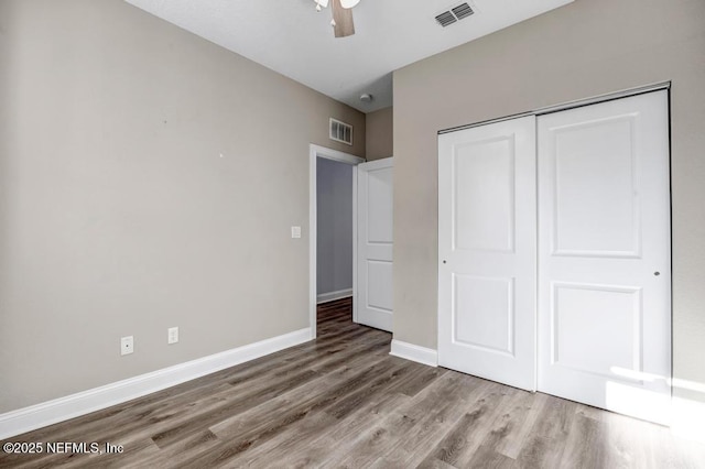 unfurnished bedroom with ceiling fan, wood-type flooring, and a closet