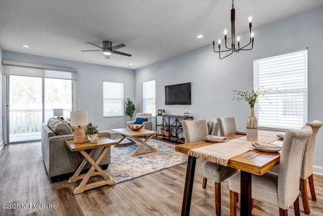 living room featuring a healthy amount of sunlight, light hardwood / wood-style floors, and ceiling fan with notable chandelier