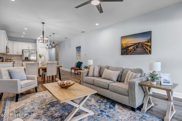 living room featuring hardwood / wood-style flooring and ceiling fan with notable chandelier