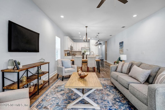 living room featuring sink, hardwood / wood-style flooring, and ceiling fan with notable chandelier