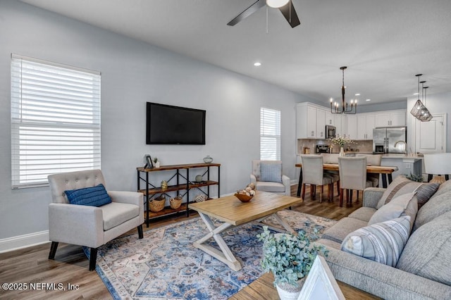 living room with hardwood / wood-style flooring and ceiling fan with notable chandelier