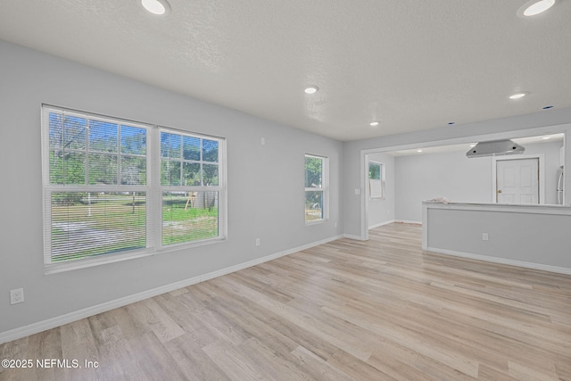 unfurnished living room with light hardwood / wood-style flooring and a textured ceiling