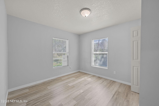 empty room with light wood-type flooring and a textured ceiling