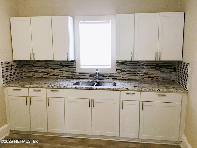 kitchen featuring white cabinets, a sink, and backsplash