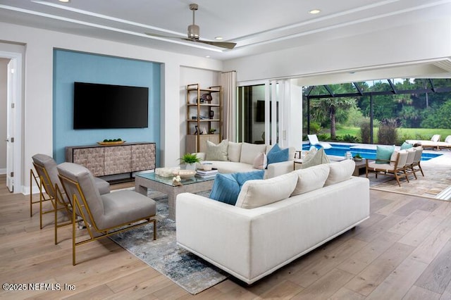 living room with a tray ceiling, light hardwood / wood-style flooring, and ceiling fan