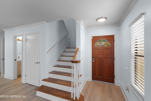 entrance foyer featuring stairs, baseboards, light wood-style floors, and crown molding