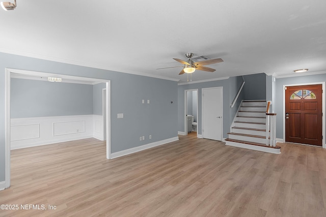 unfurnished living room featuring light wood finished floors, visible vents, ceiling fan, stairs, and ornamental molding