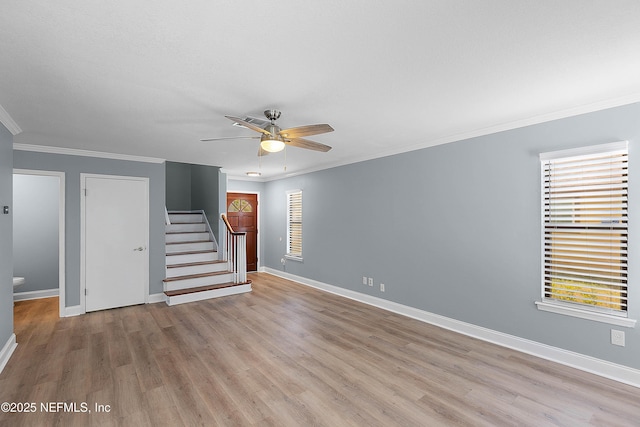 unfurnished living room with stairway, baseboards, light wood-style floors, and crown molding