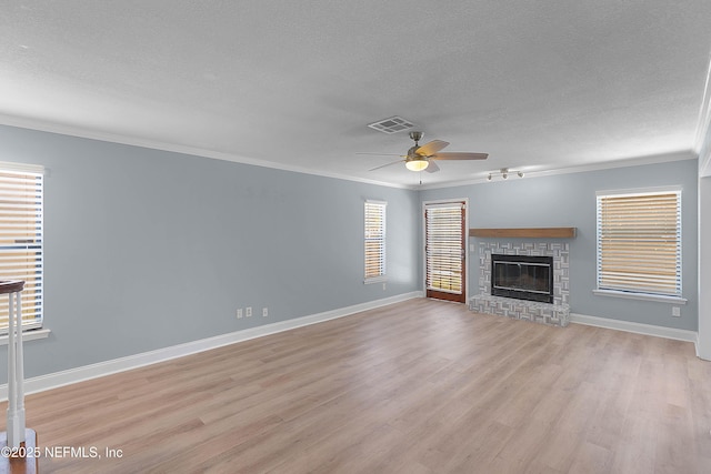 unfurnished living room featuring a glass covered fireplace, a healthy amount of sunlight, light wood-type flooring, and crown molding